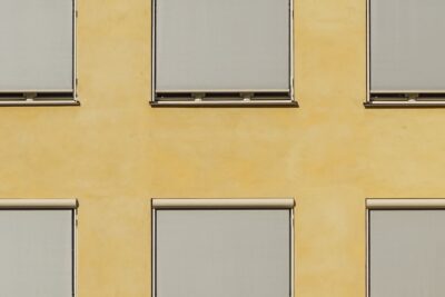 Modern building facade in Oslo with minimalist ochre walls and closed blinds creating a geometric pattern.